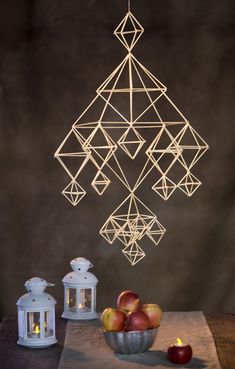 a table topped with an apple next to a bowl of apples and a lantern hanging from the ceiling