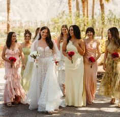 a group of women standing next to each other on a road with palm trees in the background