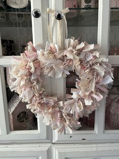 a wreath on the front door of a house with pink and white ribbons hanging from it