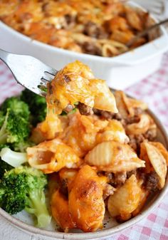 a fork in a dish with broccoli and cheesy casserole