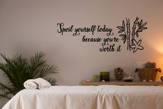 a white bed sitting next to a wall with writing on it and a potted plant in the corner