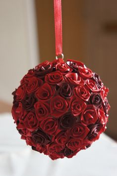 a ball shaped ornament with red roses hanging from it's side on a table