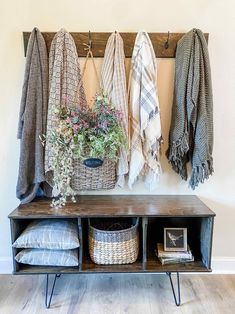 a coat rack with several coats hanging on it and some flowers in the basket next to it