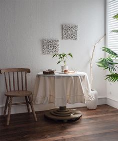 a table with a white cloth on it next to a chair and potted plant