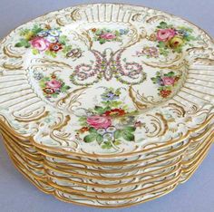 a stack of gold and white plates with floral designs on them, all stacked together