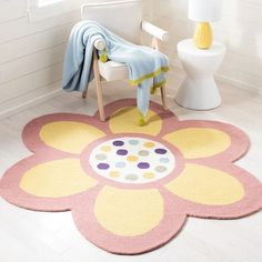 a bathroom with a flower rug on the floor next to a white toilet and chair