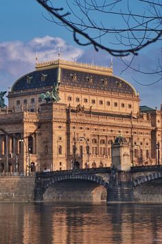 a large building sitting on top of a river next to a bridge