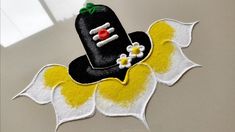 a black hat with yellow and white flowers on it sitting on top of a table