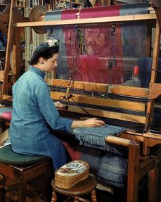 a woman is working on an old weaving machine