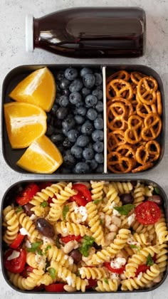 two trays filled with pasta, fruit and pretzels next to a bottle of soda