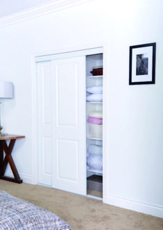 a bedroom with white walls and carpeted flooring has an open closet to the left