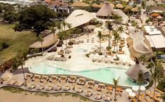 an aerial view of a resort with many pools and cabanas in the background