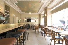 the interior of a restaurant with tables and chairs lined up against the wall, in front of an open window