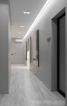 an empty hallway with white walls and wood flooring is lit by recessed lighting