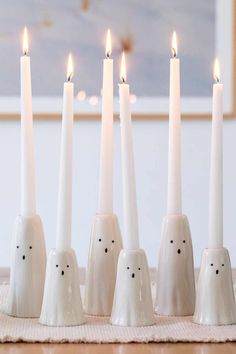 five white candles are lined up in the shape of ghost heads