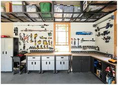 an organized garage with lots of tools on the wall and cabinets in front of it