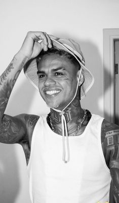 a black and white photo of a man with tattoos on his face wearing a hat