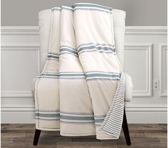 a white chair with a blue and white striped blanket on it's back next to a wall