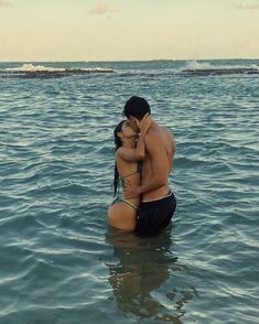 a man and woman are kissing in the water at the same time as they stand close to each other