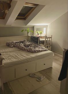 a bed sitting in the middle of a room under a slanted ceiling with two pillows on top of it