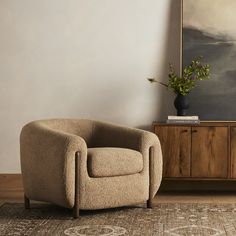 a chair sitting on top of a wooden floor next to a painting