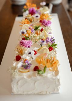 there is a long cake with flowers on it