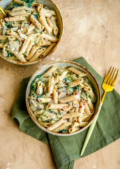 two bowls filled with pasta on top of a green napkin