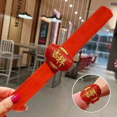 a person holding up a red wristband with chinese writing on it in a restaurant