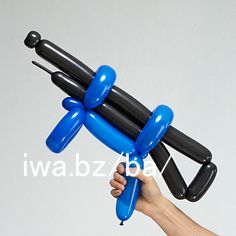 a hand holding an inflatable black and blue balloon with two smaller balloons attached to it