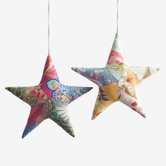 two decorative stars hanging from strings on a white background, one is multicolored and the other has floral designs