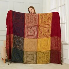 a woman is holding up a multicolored blanket