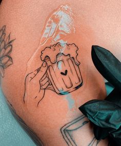 a person with tattoos on their stomach holding a beer mug