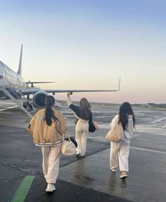 three women walking towards an airplane on the tarmac