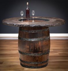 a wine bottle and two glasses sitting on top of a wooden barrel table with marble top