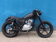 a black motorcycle parked in front of a blue wall