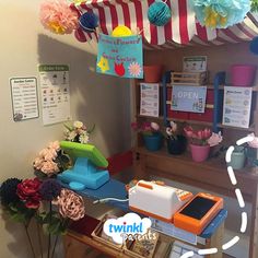 an image of a flower shop with flowers on the shelf and decorations hanging from the ceiling