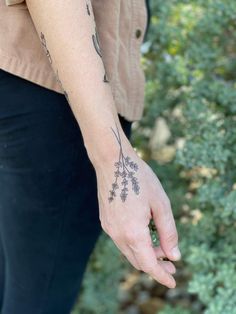 a person with a tattoo on their arm holding something in her hand and looking down at the ground