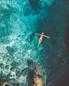 a woman is swimming in the water near some rocks