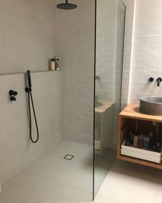 a walk in shower sitting next to a white tiled wall and wooden stand up shower head