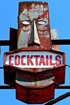 an old neon sign that says cocktails with a mask on it's face