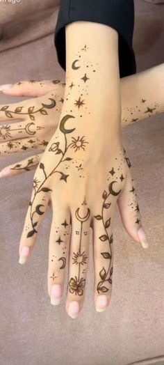 a woman's hand with tattoos on it and stars, moon and crescents