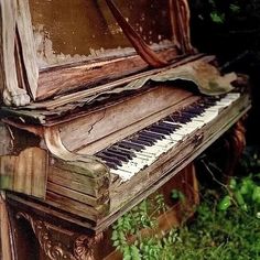 an old piano sitting in the middle of some grass and weeds, with peeling paint on it