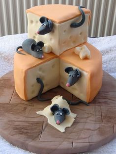 a cake made to look like cheese with mice on it and two pieces of cheese in the middle