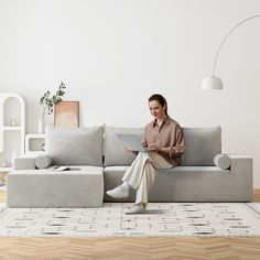 a woman sitting on a couch with a laptop in her hand and looking at the screen