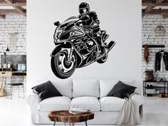 a living room with a white couch and a motorcycle wall decal on the wall