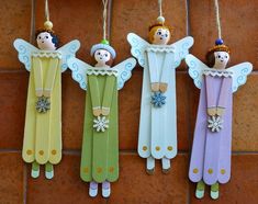 three wooden angel ornaments hanging from strings on a brick wall next to a tile floor