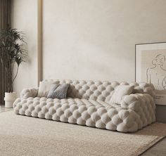 a white couch sitting on top of a rug in a living room next to a potted plant