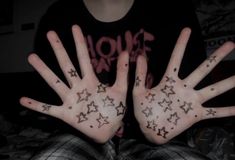 two hands with stars painted on them are shown in front of a person's face