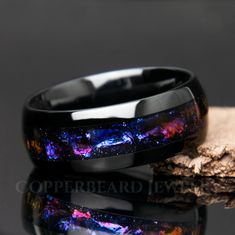 "This black galaxy ring is gorgeous! It features a mesmerizing design reminiscent of swirling gas and dust clouds found in galaxies, this ring boasts a stunning array of colors that evoke the celestial splendor of the night sky. Deep blues, purples, pinks, and oranges come together in a breathtakingly beautiful pattern, creating a sense of cosmic movement and dynamism that is sure to captivate the imagination. Beautiful color shifting effect! || Features || - Solid and strong tungsten band - Dom Space-themed Black Jewelry Gift, Galaxy Rings, Promise Ring Men, Fantasy Jewelry Magic, Blue Sandstone Ring, Stars Beautiful, Sandstone Ring, Cosmic Ring, Ceramic Wedding