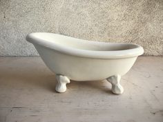 a white bathtub sitting on top of a wooden floor next to a gray wall